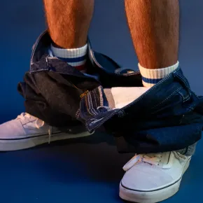 man met broek op de enkels